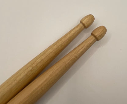 Two wooden drumsticks on a light gray background