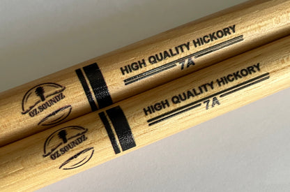 Two wooden drumsticks with 'Oz Soundz' branding and 'High Quality Hickory 7A' text on a neutral background.