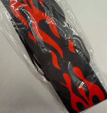 Black and red flame-patterned guitar strap in clear plastic packaging on a white background