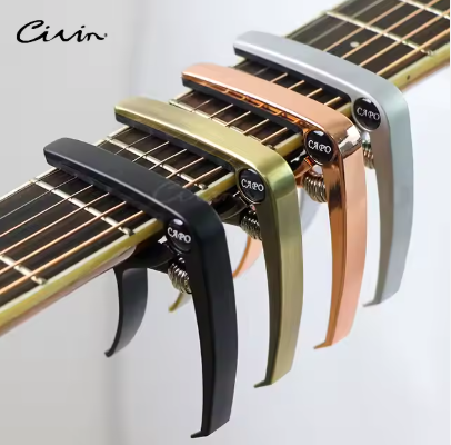 Set of guitar capos in various colours on a guitar neck on white background