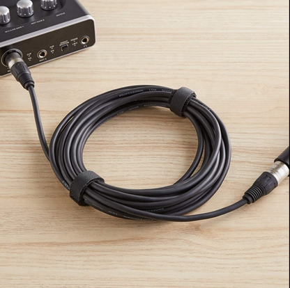 Black audio cable connected to an audio interface on a wooden surface